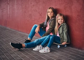 Портрет Двух Милых Сестричек Одетых Модную Одежду Прислонившихся Стене Сидящих — стоковое фото