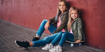 Портрет Двух Милых Сестричек Одетых Модную Одежду Прислонившихся Стене Сидящих — стоковое фото