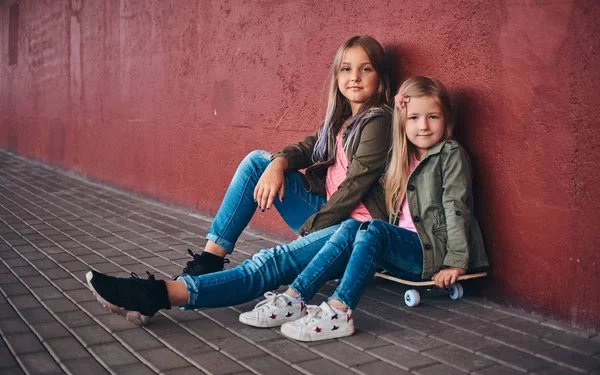Портрет Двух Милых Сестричек Одетых Модную Одежду Прислонившихся Стене Сидящих — стоковое фото