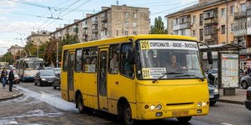 типичный желтый одесский автобус «Богдан» №201, застывший в заторе на одной из улиц города. Кабина водителя украшена деталями, которые сразу узнает любой одессит — например, герб города, флажок Украины и винтажные часы. На лобовом стекле четко видна табличка с номером «201» и маршрутом: «СТАРОСЕННАЯ ПЛ. — Ж/Д ВОКЗАЛ — ЛЕНПОСЕЛОК